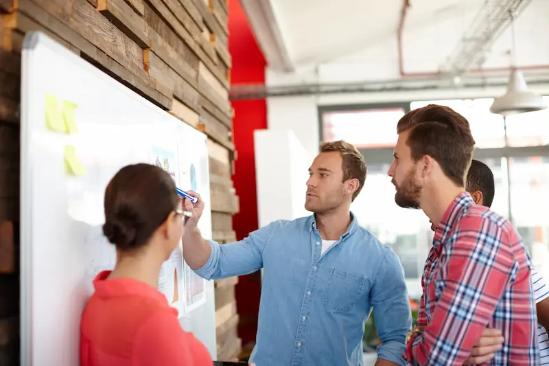 Mapping out product discovery strategy on a whiteboard with tech scale-up team